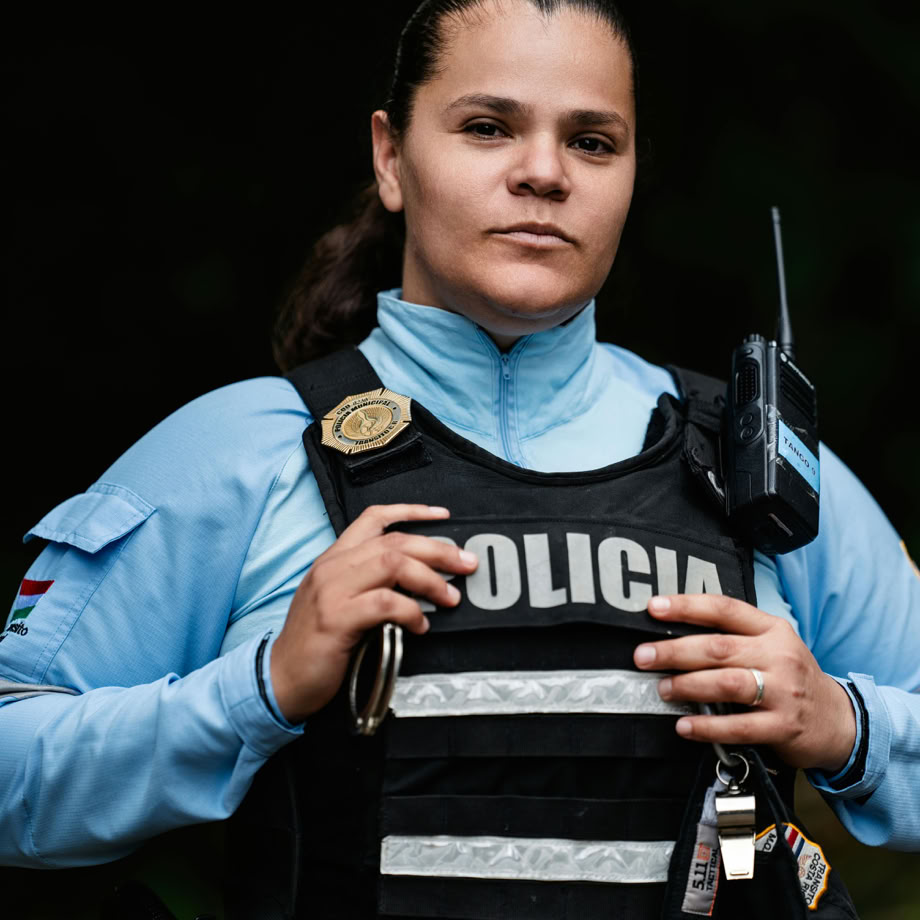 A female police officer in uniform standing confidently in an outdoor setting, showcasing law enforcement presence.