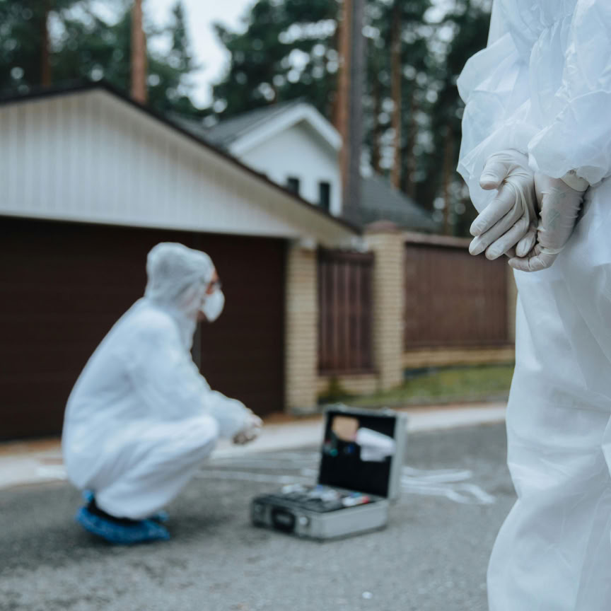 Forensic investigators in white suits and masks examining a crime scene outside a residential area.